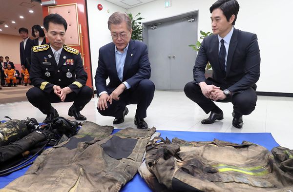 지난 6월 7일 오전 서울 용산소방서를 방문한 문재인 대통령이 소방관의 낡은 근무복을 살펴보고 있다. 사진 출처: 청와대 홈페이지