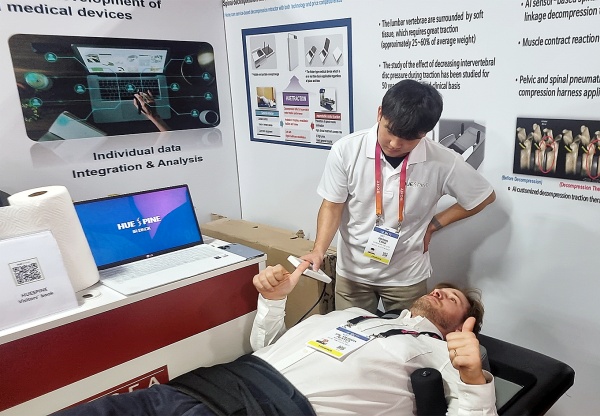 CES 2023 참가자가 휴스파인 부스에서 AI 척추 감압 견인기를 체험하고 있다.